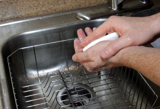 A man washing his hands with soup in a sink.