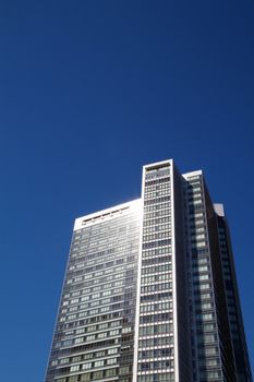 Bright sun reflected off offfic e building with green tinted windows against deep blue sky