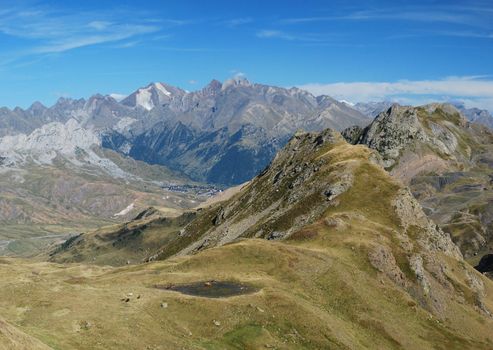 Panorama of Pyrenees mountains in Spanich Aragon, El Formigal village, Peak Enferno 3082 m, seen from Anayet plateau in summer time, there are cows and horses at the lake in the middle