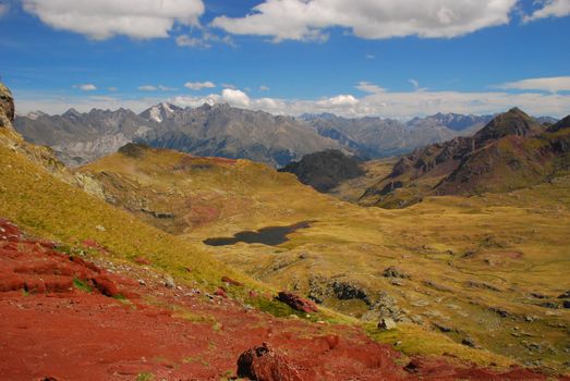 Spectacular vue at Anayet plateau, lake and Spanich Pyrenees from slope of Anayet Plateau. The red rockq at foreground, and mountain chain with famous Peak Enfer 3082 m at foreground