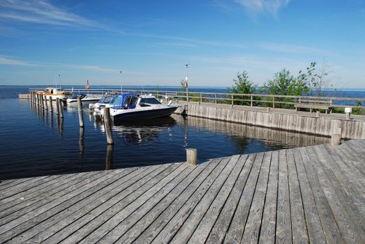 Motor boats are at boat station with nice wooden foot-path in the camping of Manamansalo island in the lake  Oulujarvi, Kainuu region, Finland. 