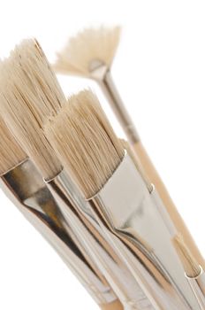 Close up capturing a selection of artist brushes against white.