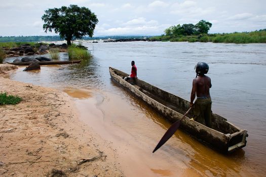 Two men float in a wooden boat on the river Congo