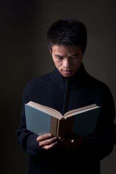 Chinese college student reading a book in sweater