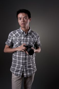 A young Asian man holding a SLR camera