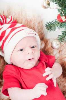 Newborn baby in chritstmas hat lies on fur