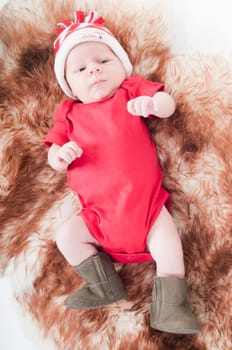 Newborn baby in chritstmas hat lies on fur