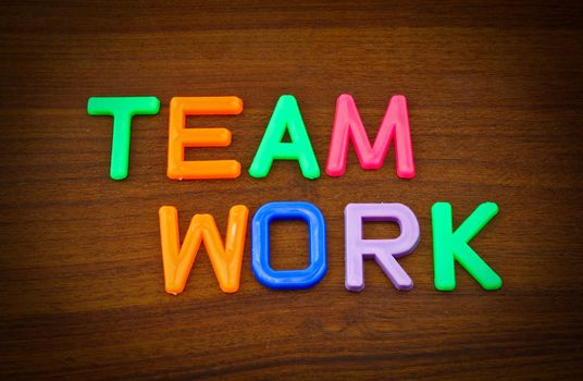 Team work in colorful toy letters on wood background
