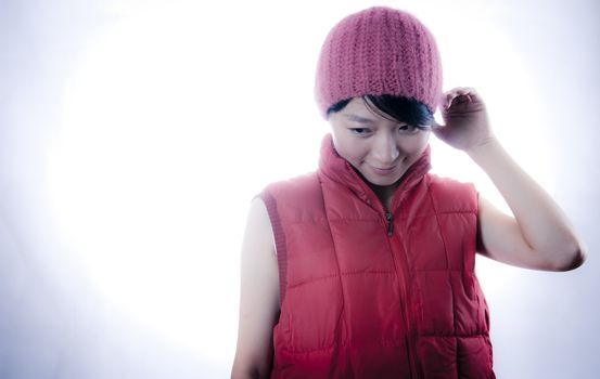 Shy Asian girl with vest and winter hat isolated on white