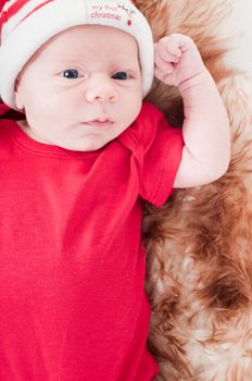 Newborn baby in chritstmas hat lies on fur