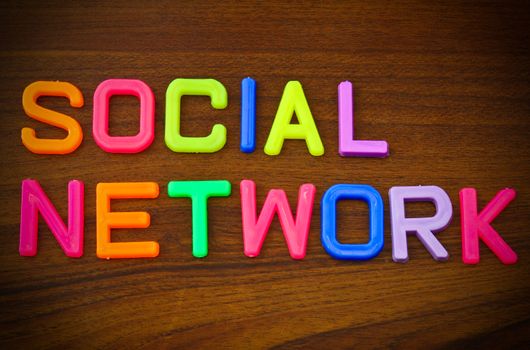 Social network in colorful toy letters on wood background
