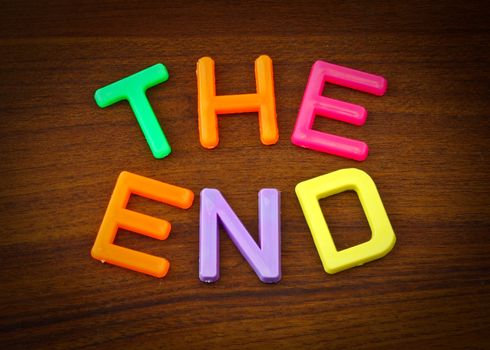 The end in colorful toy letters on wood background