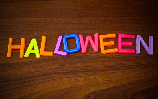 Halloween in colorful toy letters on wood background