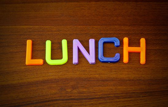 Lunch in colorful toy letters on wood background