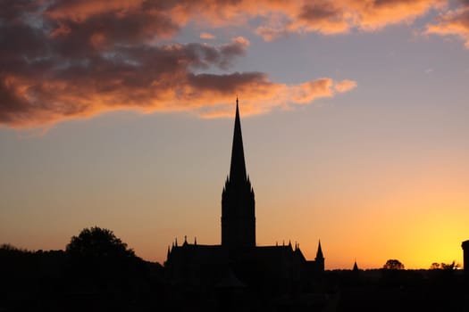 A winter sunset over Salisbury Cathedral in the city of Salisbury, Wiltshire. The cathedral silhouetted against low winter clouds.