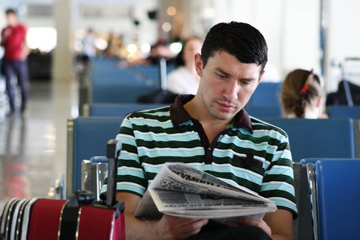 Man reading newspaper while sitting at the airport