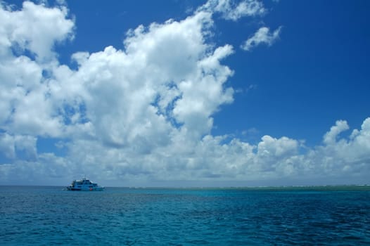 boat in distance, great barrier reef in australia, blue sky and water