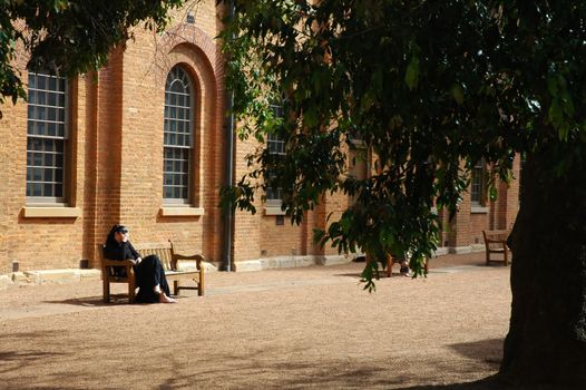 mourning woman sitting on a wooden bench in front of a church