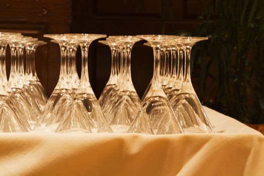 Crystal glassware is lined up on linen tablecloth in preparation for an elegant celebration;