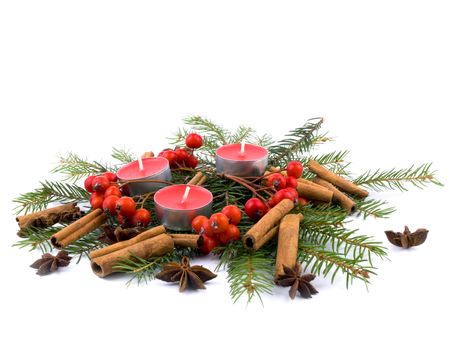 Christams composition made from three small red candles, rowan, spruce, cinnamon and anise on white background