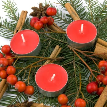 Christams composition made from three small red candles, rowan, spruce and anise