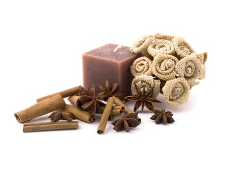 Aromatic cinnamon, anise, handemade flowers and brown candle on white background