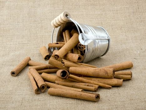 Aromatic cinnamon in small bucket on linen background