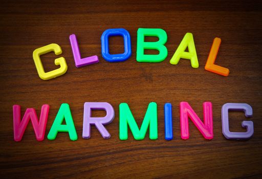 Global warming in colorful toy letters on wood background