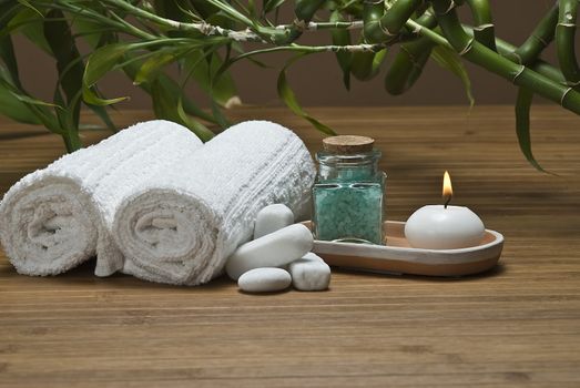 Spa background with bath salts, towels and candles on a bamboo mat.