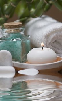 Spa background with bath salts, towels and candles on a bamboo mat.