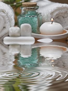 Spa background with bath salts, towels and candles on a bamboo mat.