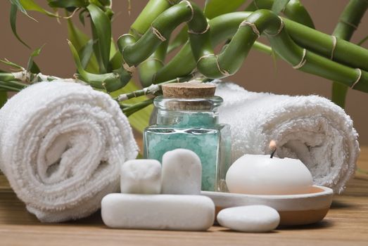 Spa background with bath salts, towels and candles on a bamboo mat.