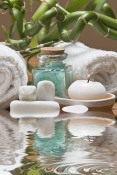 Spa background with bath salts, towels and candles on a bamboo mat.