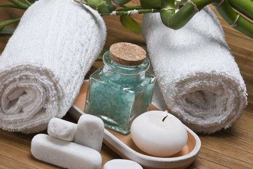 Spa background with bath salts, towels and candles on a bamboo mat.