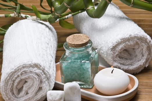 Spa background with bath salts, towels and candles on a bamboo mat.