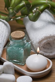 Spa background with bath salts, towels and candles on a bamboo mat.