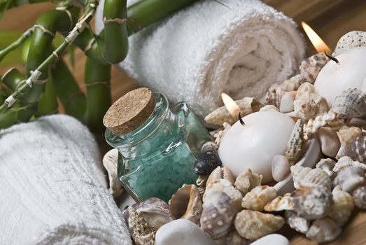 Spa background with bath salts, towels and candles on a bamboo mat.