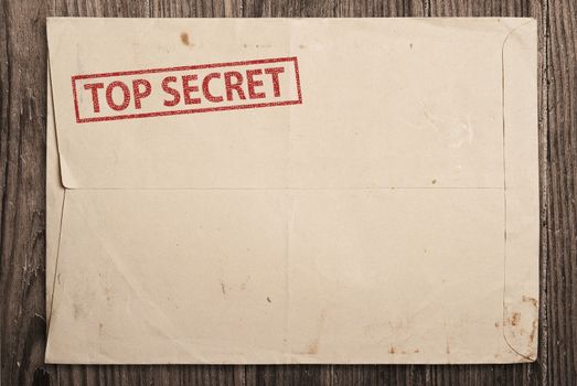 Open yellow envelope with top secret stamp and papers, on wooden table, clipping path. 