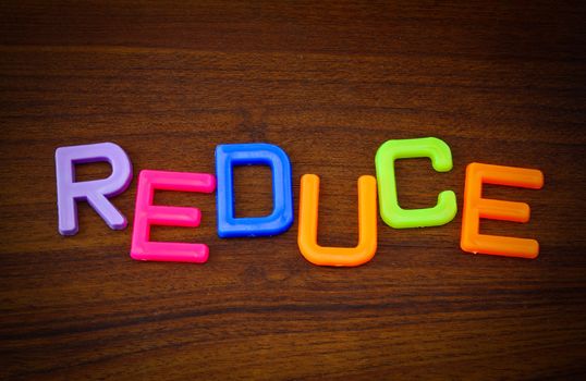 Reduce in colorful toy letters on wood background
