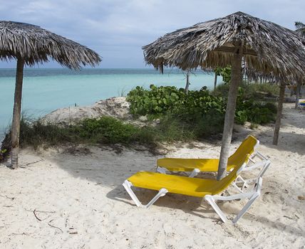 two yellow beach chair under a straw parasol