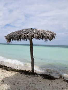 Lone straw parasol at the edge of the water