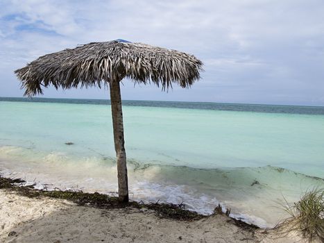 Lone straw parasol at the edge of the water