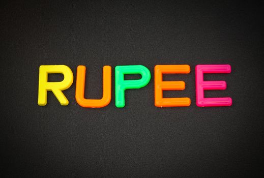 Rupee in colorful toy letters on black background