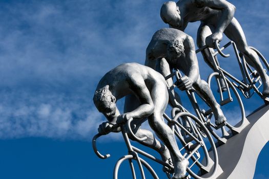 Three cyclists in a downhill, part sculpture