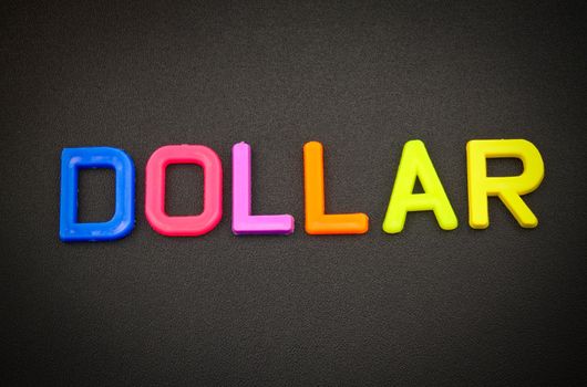 Dollar in colorful toy letters on black background
