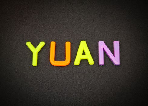 Yuan in colorful toy letters on black background