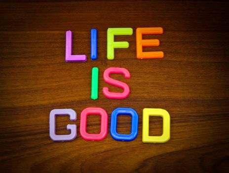 Life is good in colorful toy letters on wood background