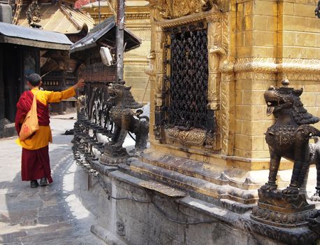 Buddhist monk praying with prayer wheels in a stupa. 