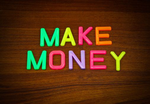 Make money in colorful toy letters on wood background