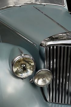 The chrome grill and headlights of an antique classic car.  Slightly desaturated for more retro feel.